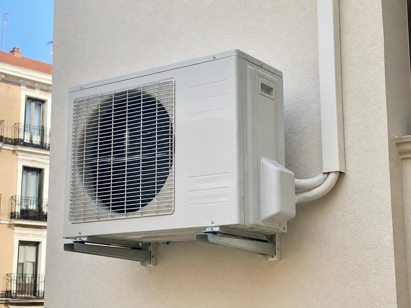 Unidad exterior de aire acondicionado instalada en la fachada de un edificio de Madrid, con soportes galvanizados y línea frigorífica canalizada